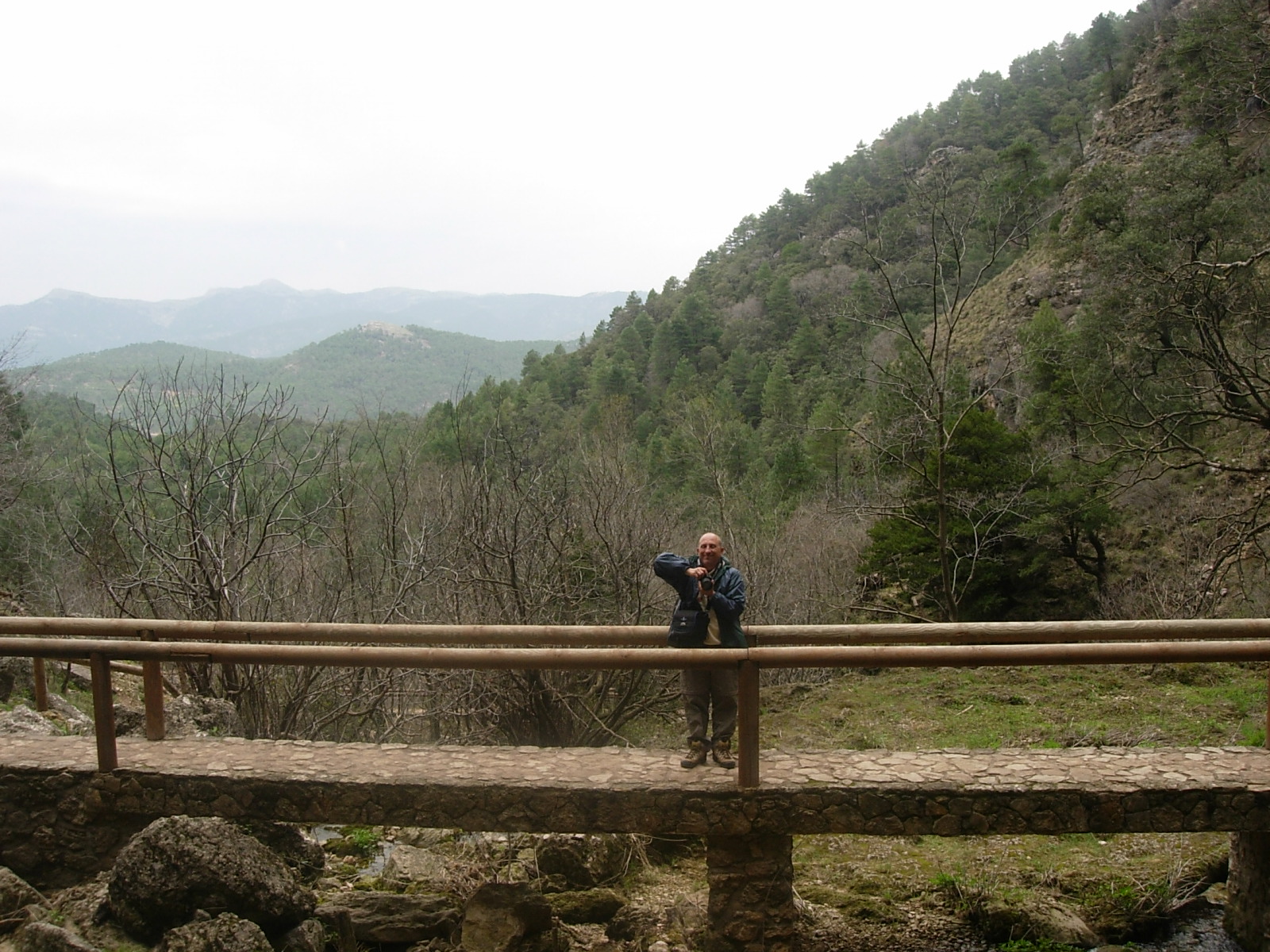 a man taking a po on a bridge overlooking a mountain