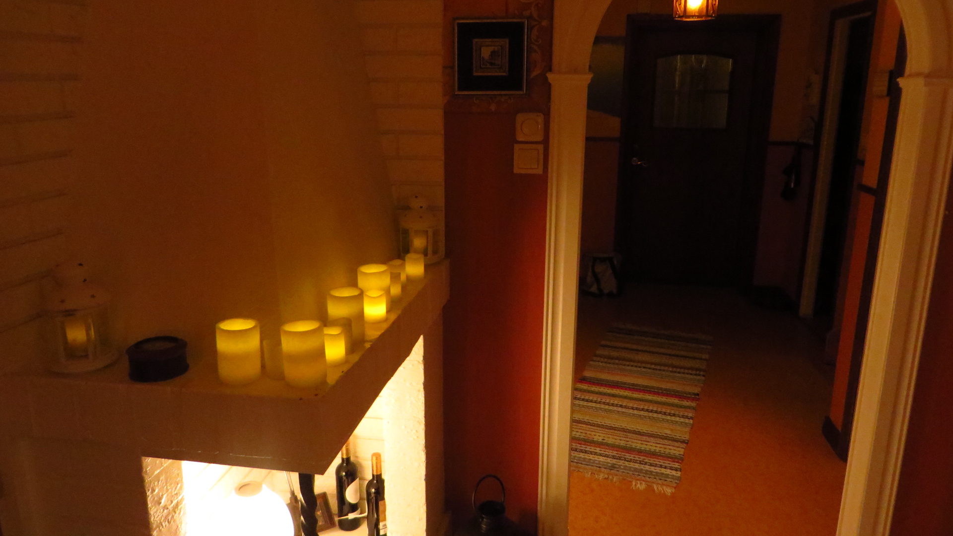 the lit candles are on the mantle in the hallway