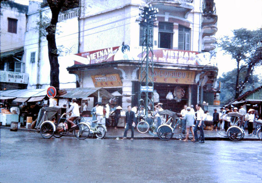 a group of men standing next to bicycles on a rainy street