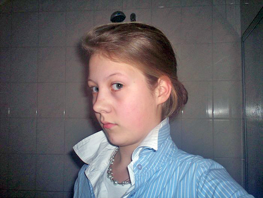 a girl stands in a public restroom wearing an unusual necklace