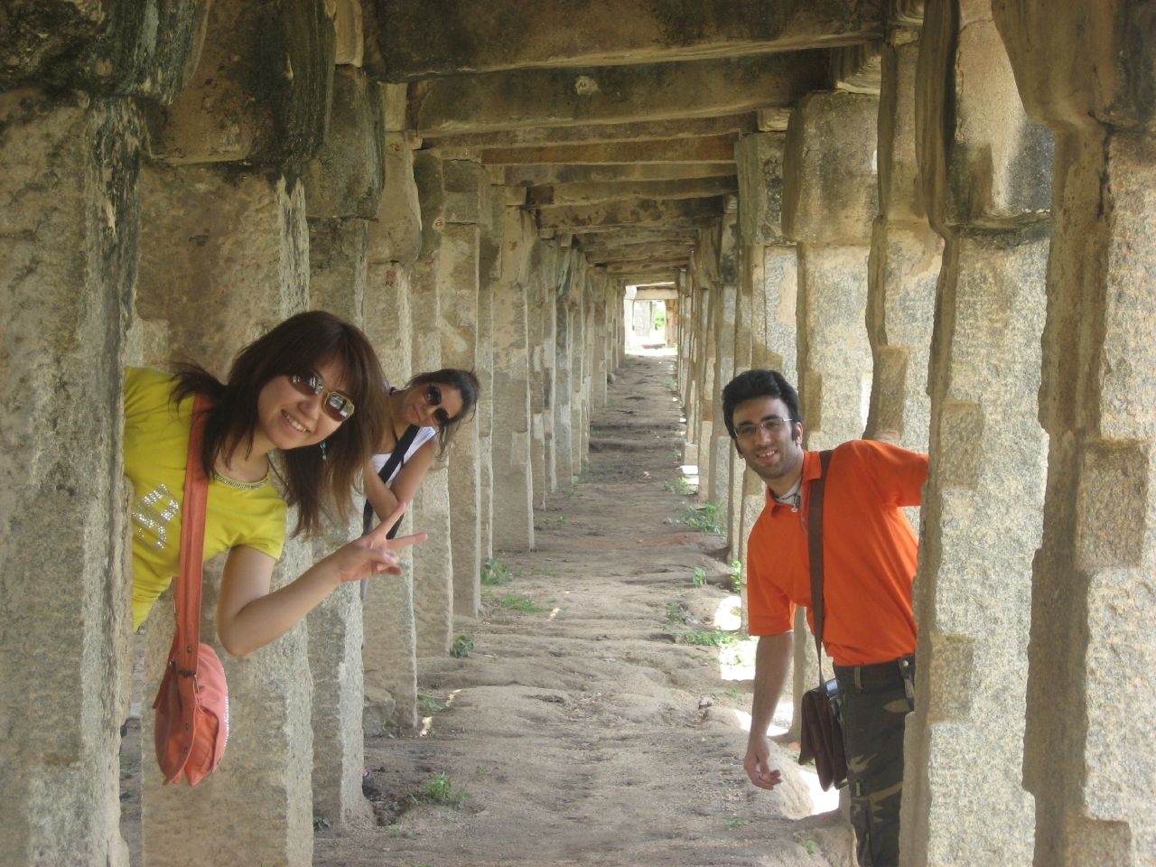 three people in orange shirts hanging off of tall columns