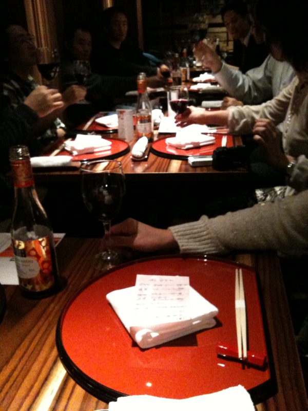 a group of people at a table eating food and drinking wine