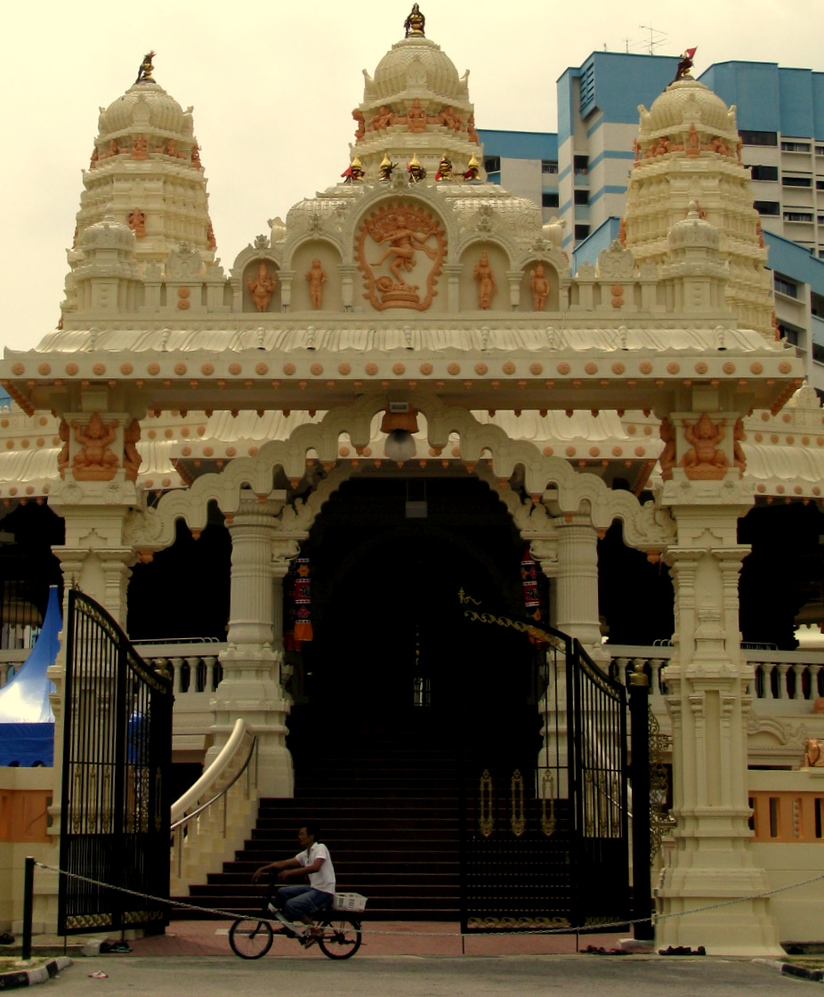 a man rides a bicycle past an ornate, elaborate structure