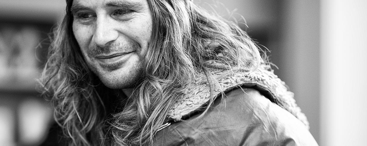 a man with long hair and beards walking in the street