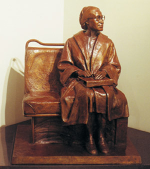 a bronze statue sitting on top of a bench