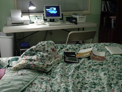 a computer desk in the corner with books and a laptop on it