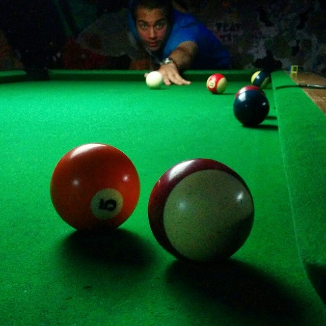 man leaning over a pool table while several billards are resting on the green cloth