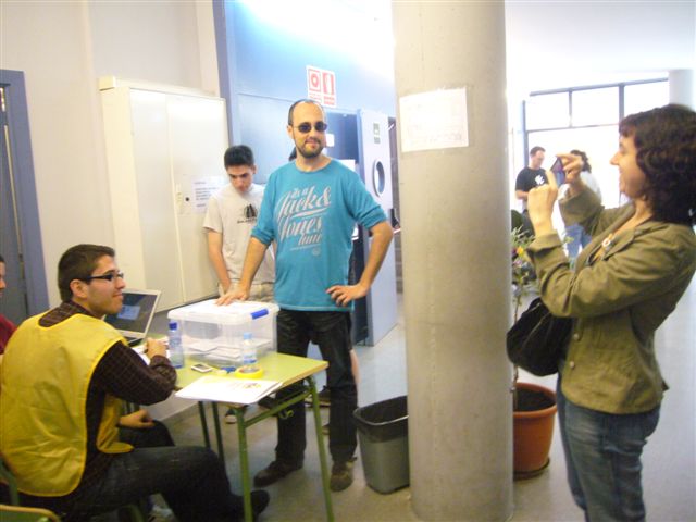 people standing around tables with laptops in an office