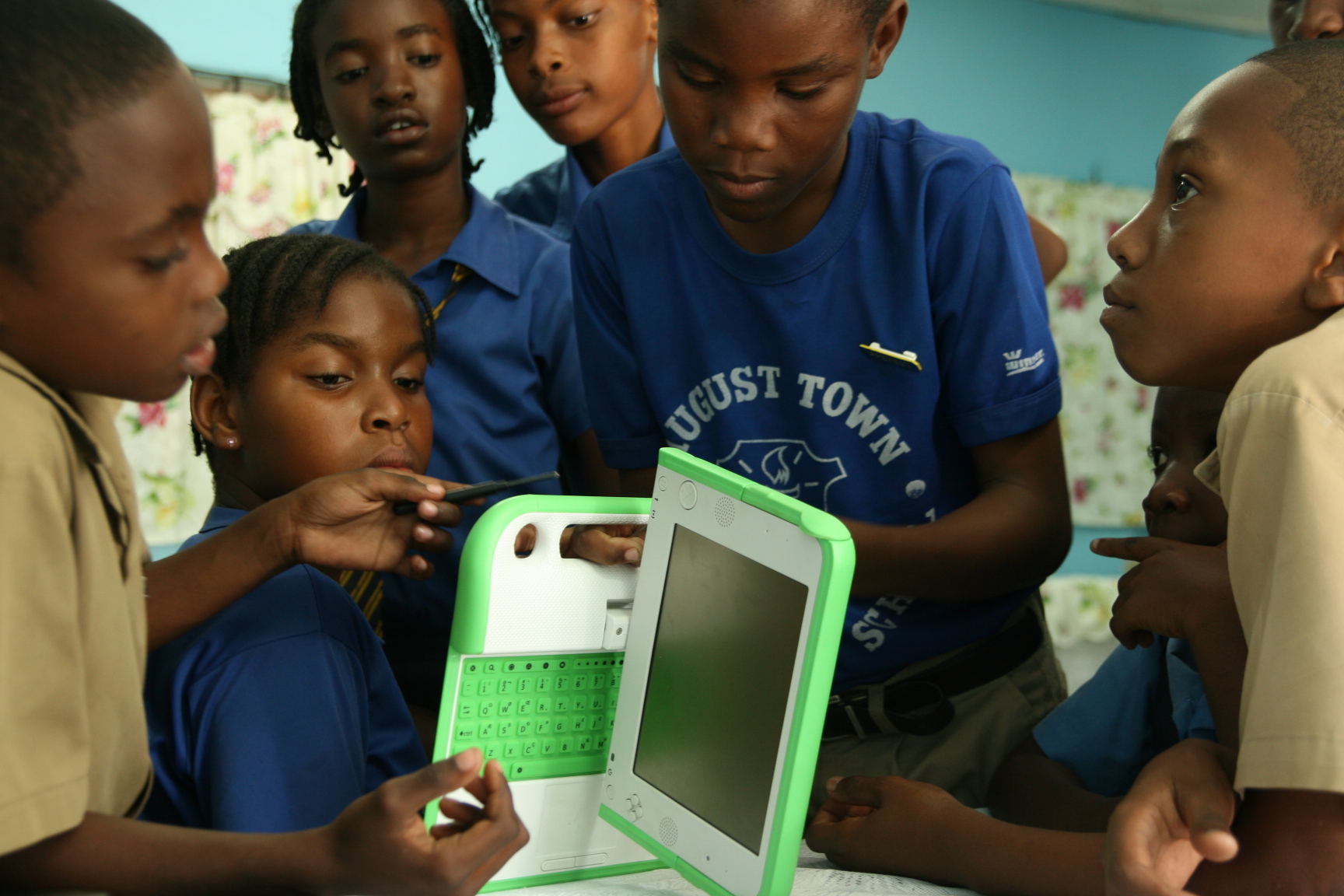 group of children looking at green and white electronic device
