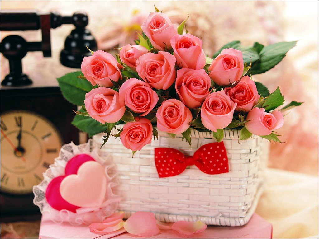 some pretty pink roses sit in a basket on a table