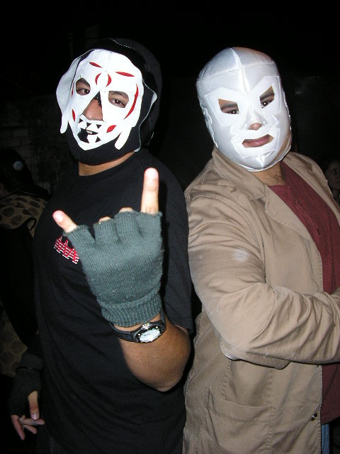 two men wearing wrestling gear and mask giving the vulcan sign