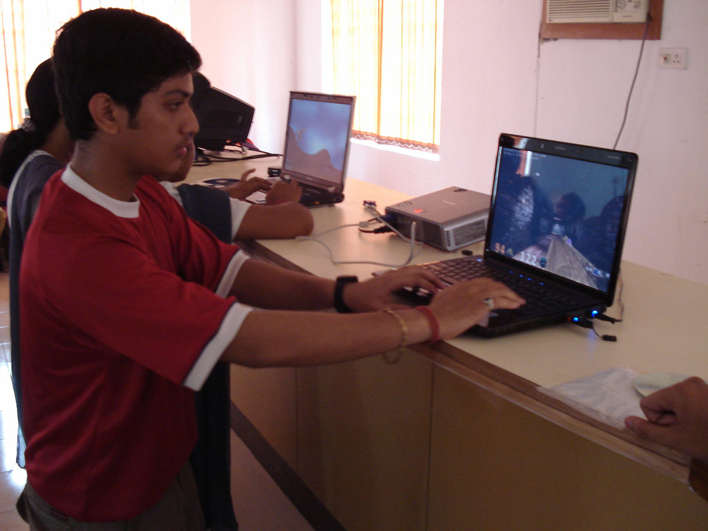a man in red shirt using a laptop on a desk
