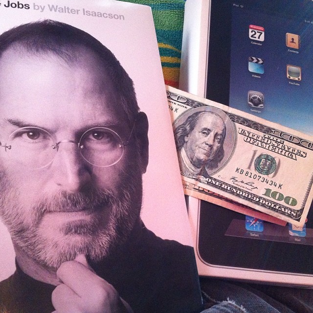 steve jobs, money and an ipad on top of a bed