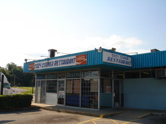 a restaurant with several stores on it and blue roof