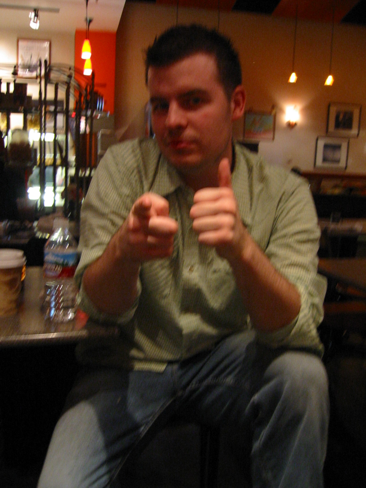 a man sitting at a table making a thumbs up sign