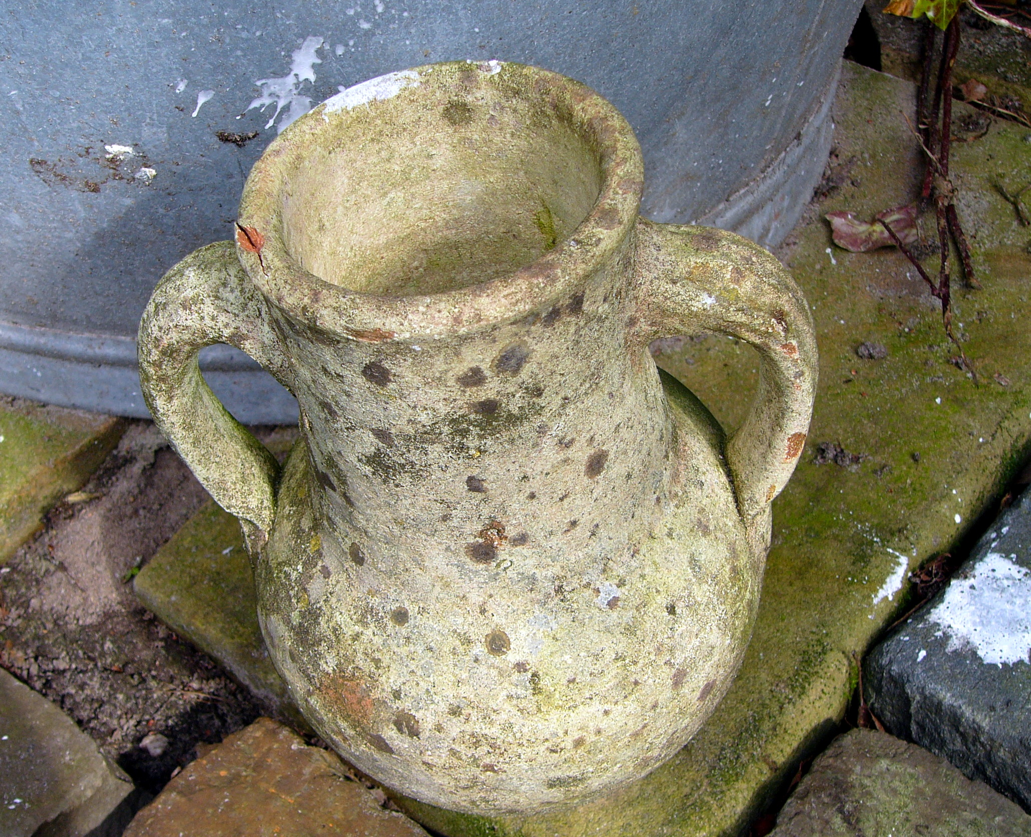 an old, dusty green pitcher is sitting on some bricks