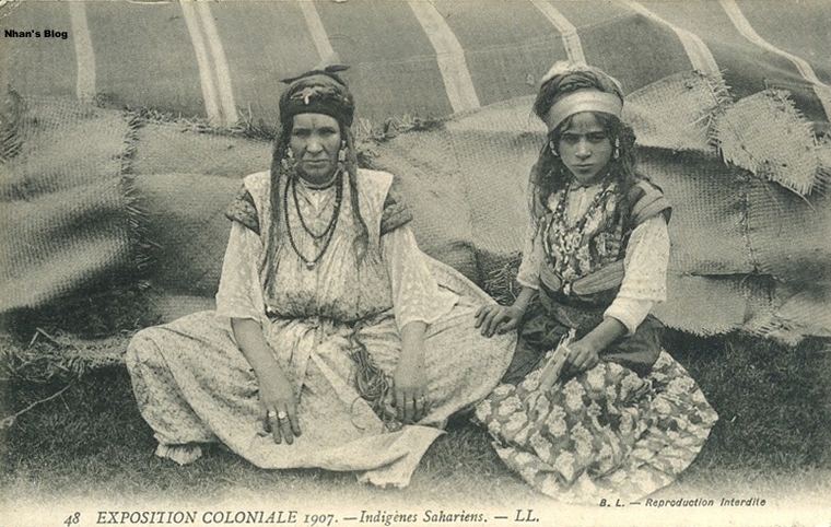 an old po of two women in native dress sitting on a bed