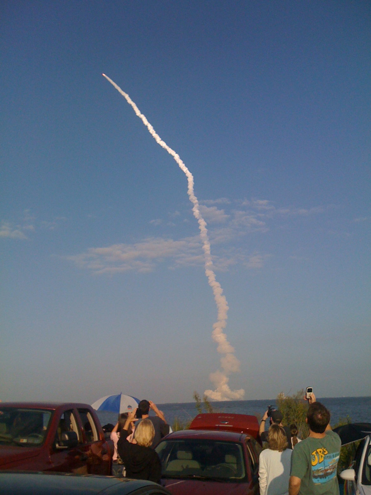 an airplane is leaving smoke behind several trucks