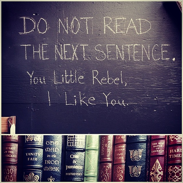 a book shelf filled with lots of books and a chalk board that reads do not read the next sentence you little right here i like you