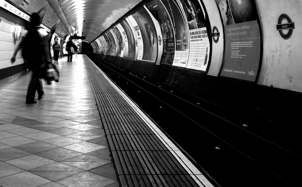 people with bags waiting on the subway platform