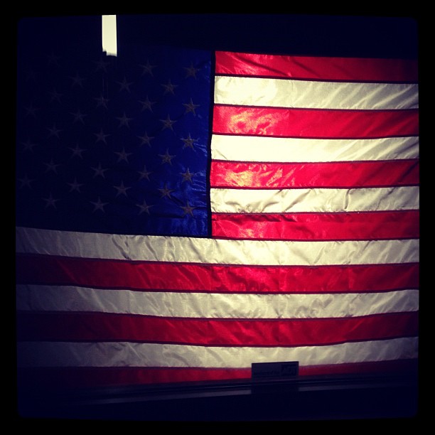 a large american flag in the dark with no star and some light