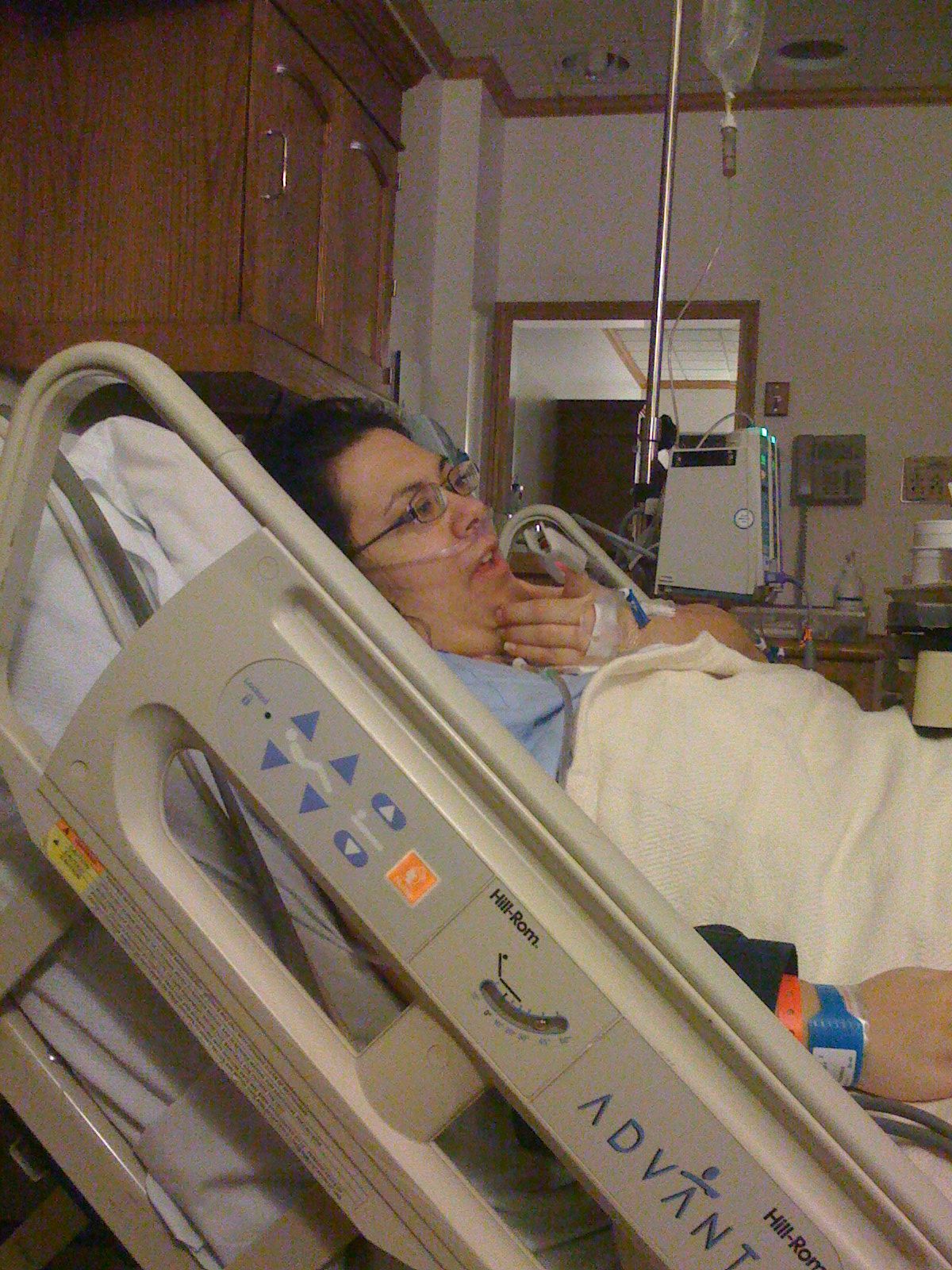 a woman sitting in a hospital bed with her hand in her mouth