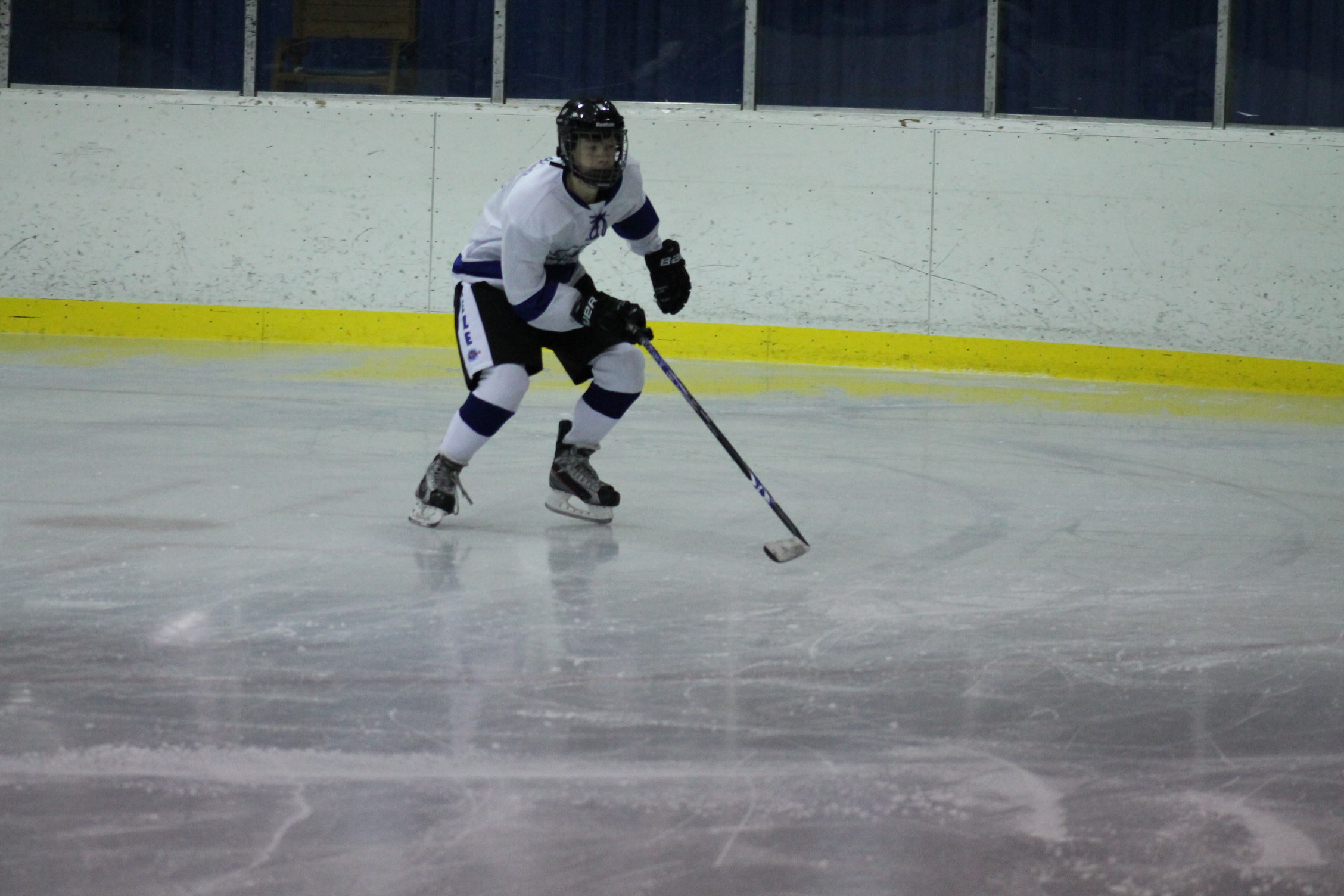 a man wearing a hockey uniform skating on an ice rink