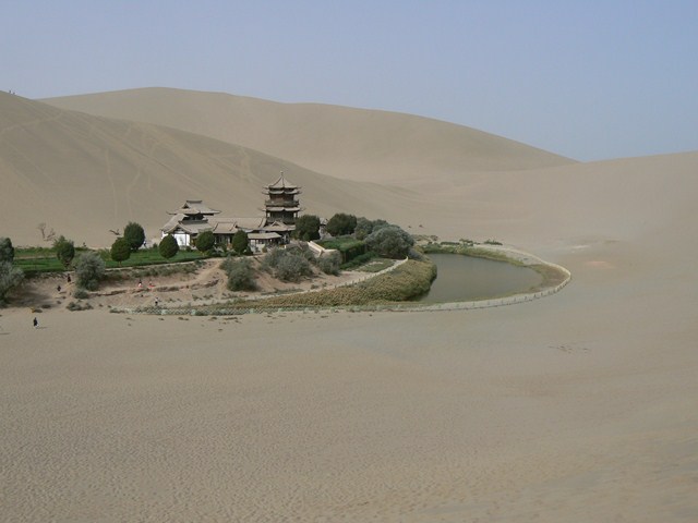 a small lake surrounded by sand dunes and vegetation