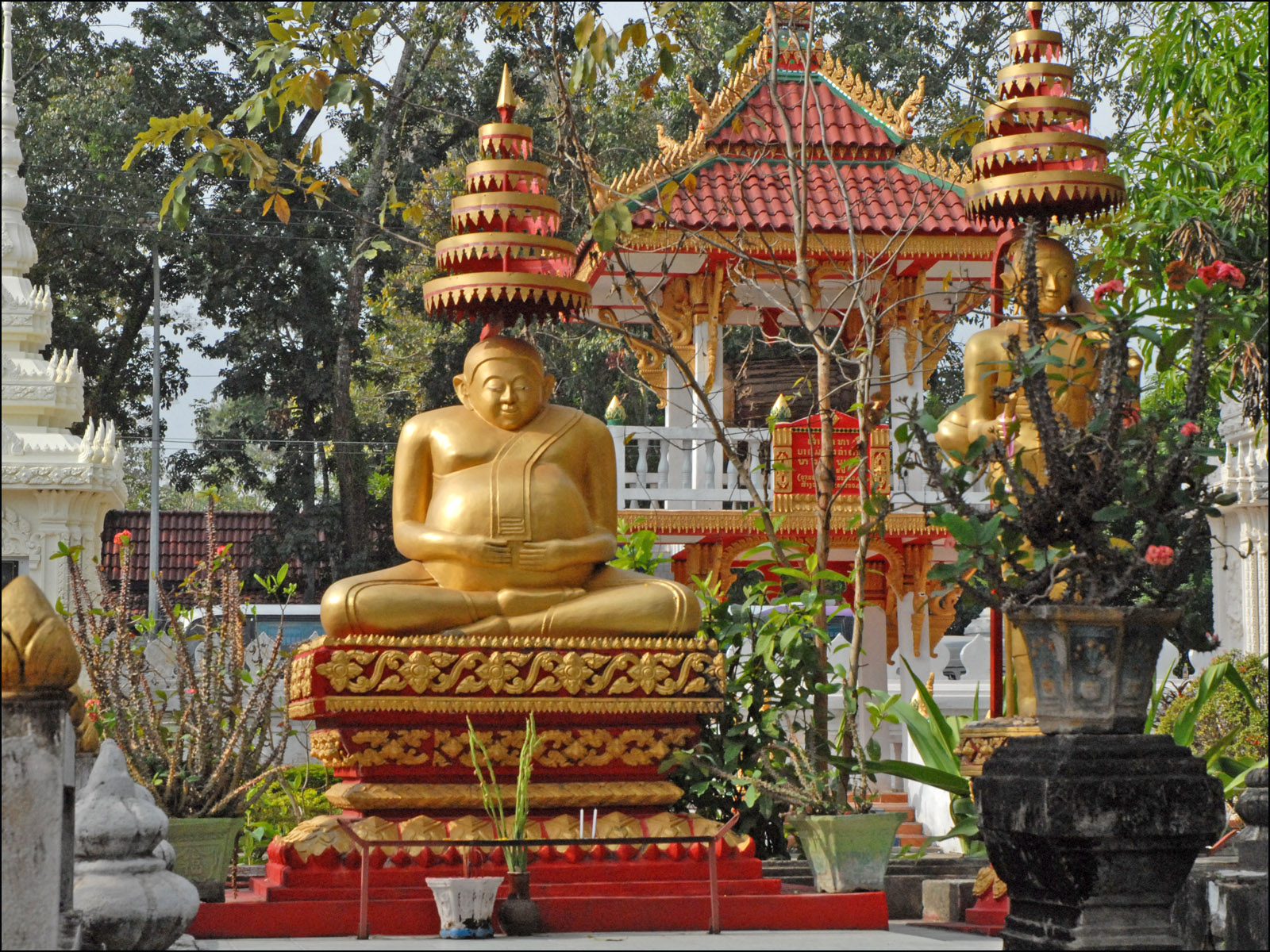 a gold buddha statue in the middle of some plants