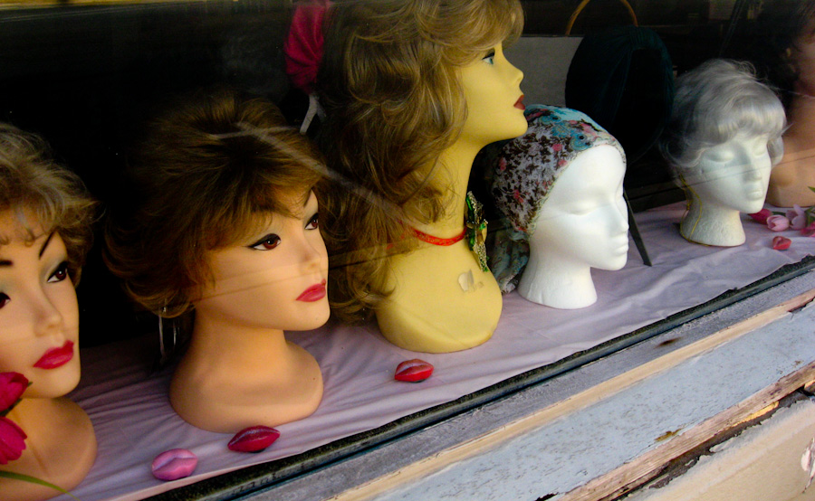 group of mannequin heads sitting on display behind glass