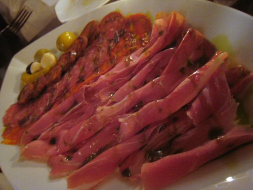 a plate of food containing ham and olives