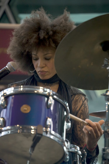 a woman with a big afro on playing drums