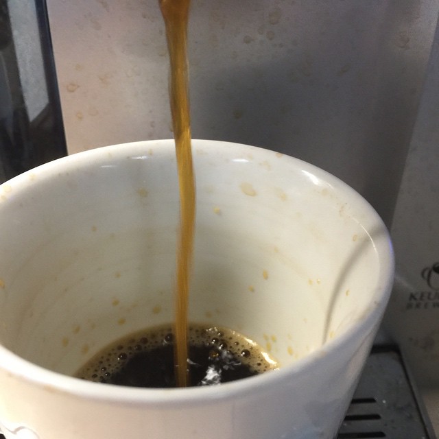 a cup filled with coffee is being filled with liquid