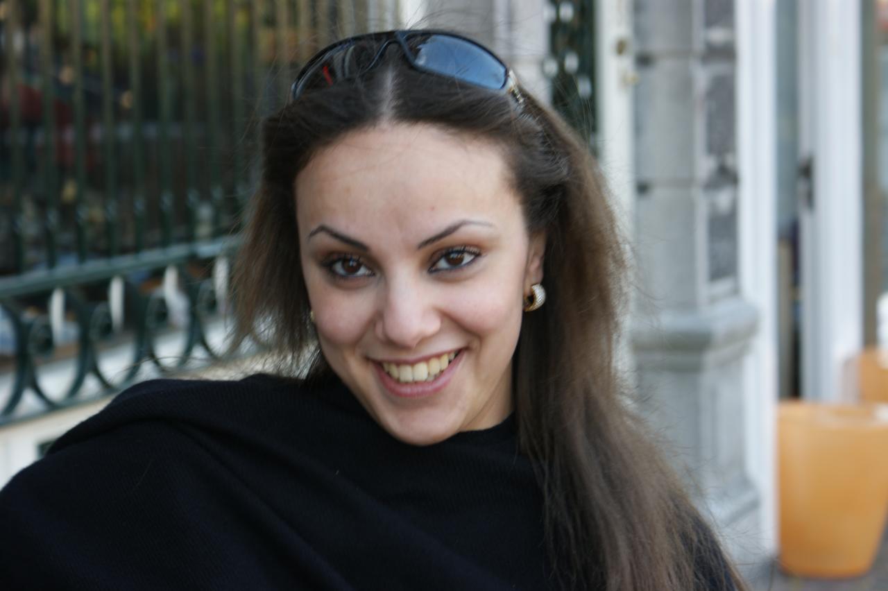 a smiling young woman has sunglasses on and looks at the camera