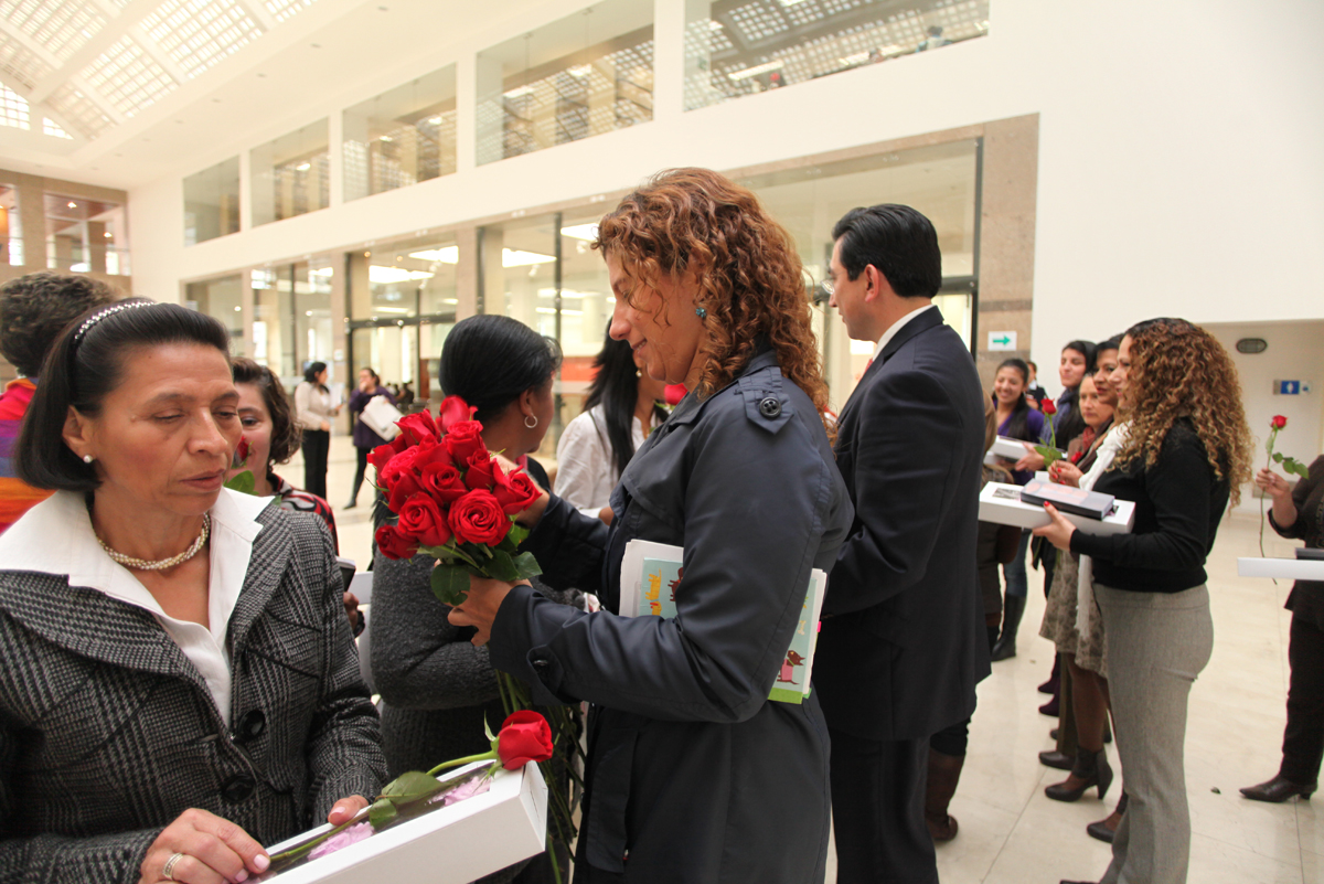 a woman is handing out roses to some women