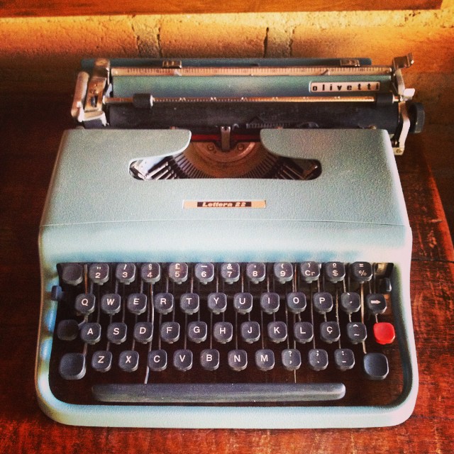 a old fashioned blue typewriter sitting on top of a wooden table