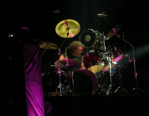 man sitting in front of a drum kit with lights on it