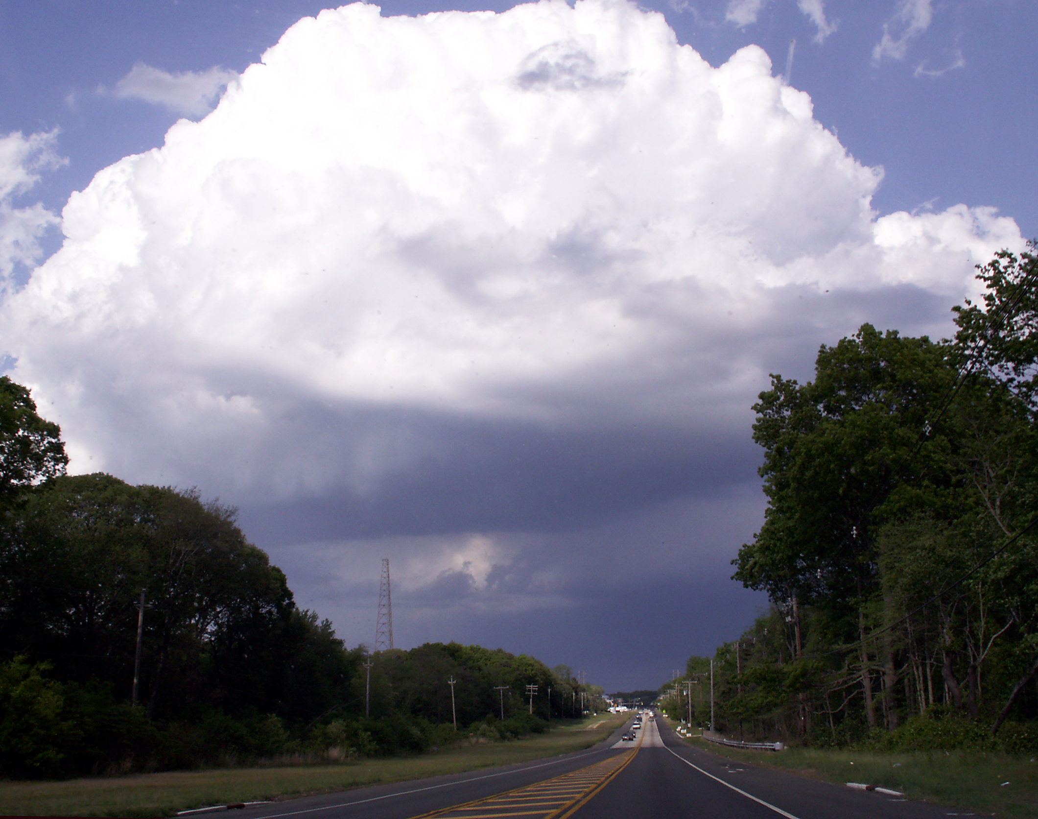 a wide road with storm clouds overhead