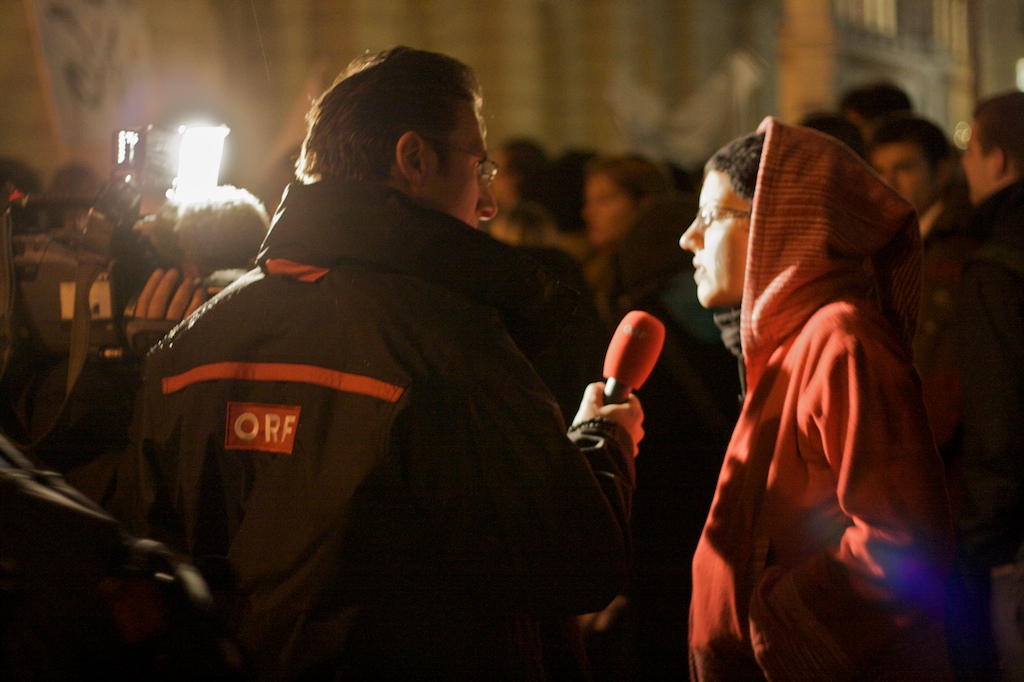 people stand around, one in red and the other in black