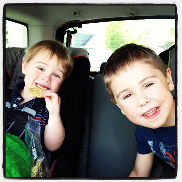 two young children sitting in a car with food