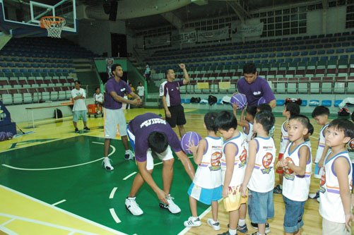 several children stand around coach in purple and white shirts