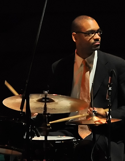 a man in a suit and tie playing drums