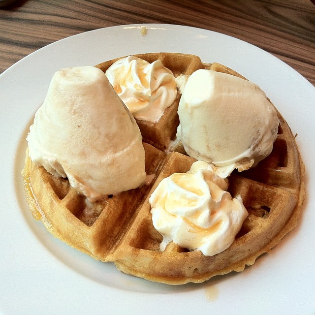 a waffle with cream and ice cream on a plate