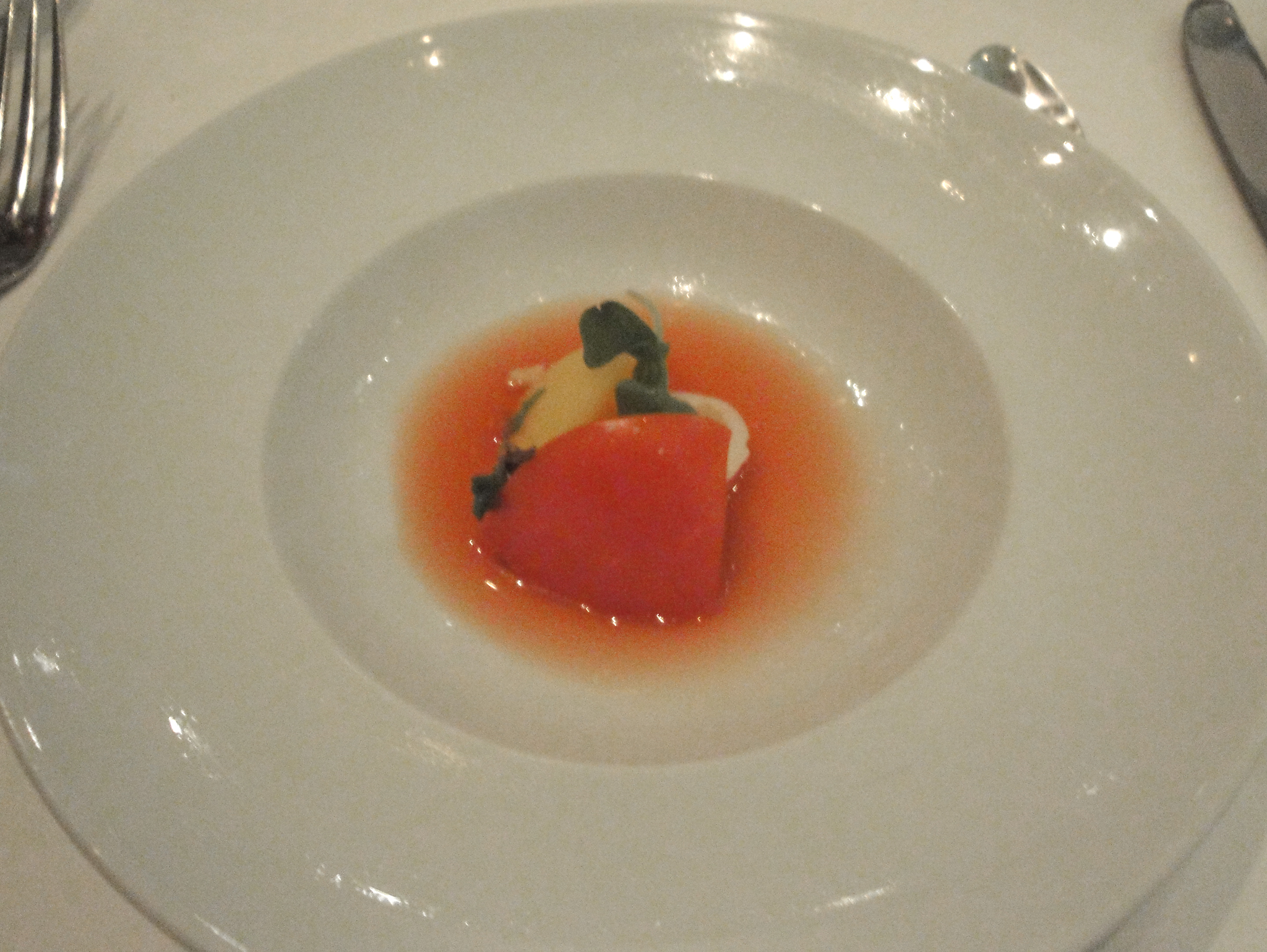 a plate with a small strawberry on it and knife and fork