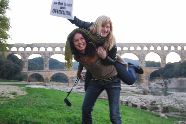 two young women walking near an old bridge