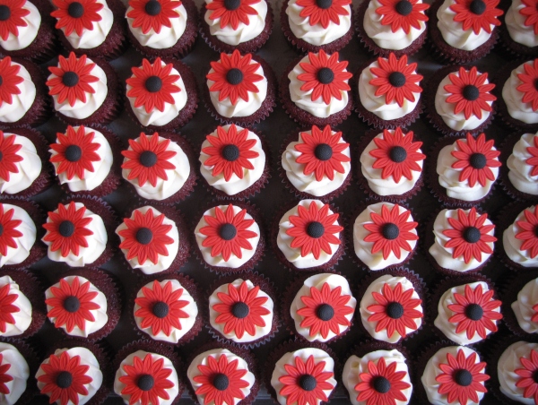 a tray of red and white cupcakes with black centers