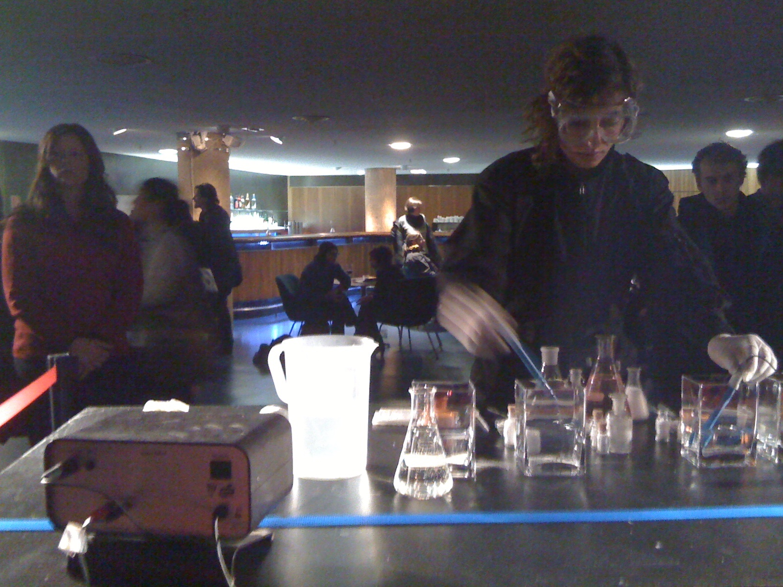 a woman pouring liquid from a pitcher into glasses