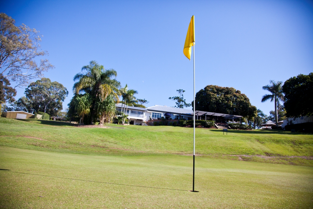 a golf green with a yellow flag and palm trees