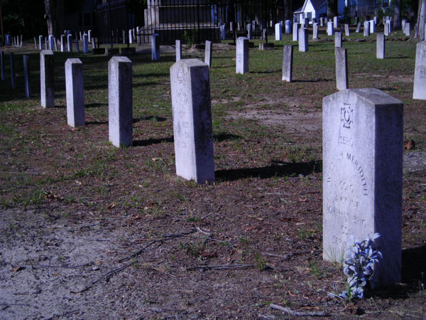 several headstones in a grave yard in front of a house