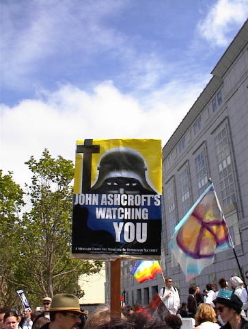 a group of people standing outside a building with a sign reading john ashcrests watching you